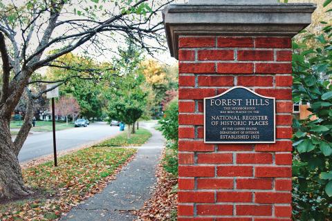 Looking down a street with a brick post showing a plaque denoting Forest Hills on the National Register of Historic Places.
