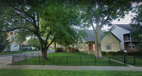 A view of several houses and a yard with a black wrought iron fence on a street corner in the Ransom Place neighborhood.